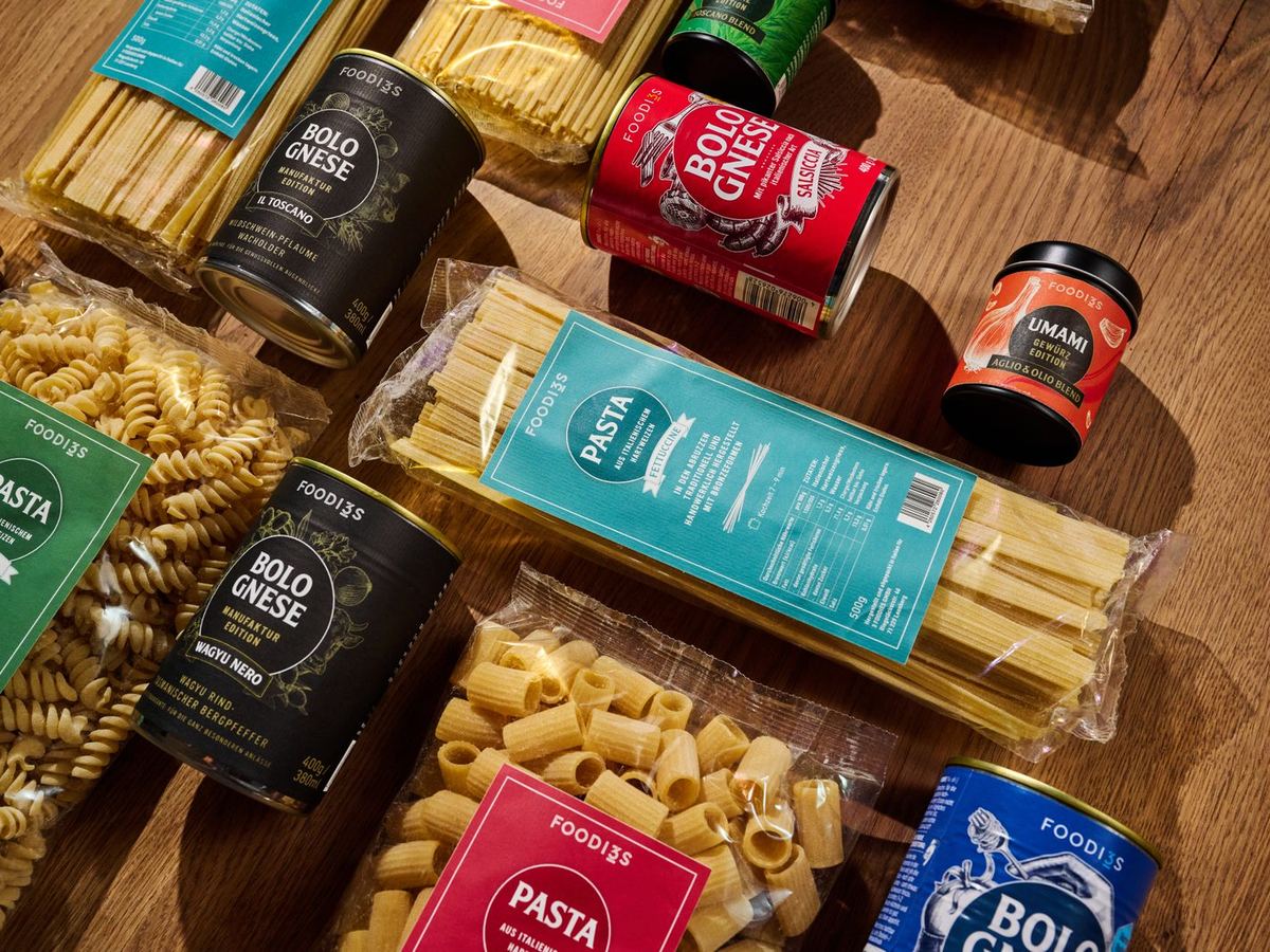 Dosen 3foodies Bolognese Il Toscano, Salsiccia, Wagyu Nero und Originale neben Pasta und Gewürz auf einem Holztisch