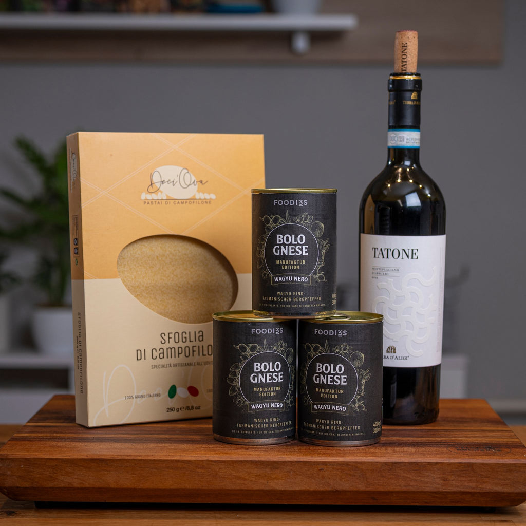 Wagyu Lasagna Special: lasagna sheets, three cans of Bolognese and a bottle of red wine on a wooden board