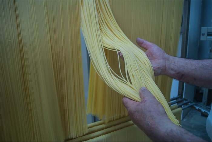 Hände legen frisch gezogene lange Pasta aus